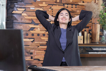 Businesswoman holding hands behind her head feeling relax after work done