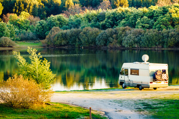 Caravan camping on lake shore with satellite dish on roof