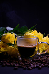 Cup of hot black coffee on coffee beans with yellow roses