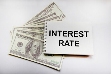 US dollars on white background with text on notepad SHOWING INCREASING INTEREST RATES FINANCIAL CONCEPT