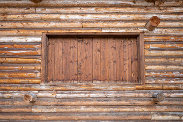 boarded-up opening in the wall of a log house. A detail of a historic wooden house
