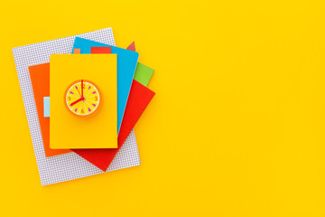 Stack of notebooks on yellow background. Top view.