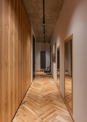 A long hallway with hardwood walls, a mirror fixture, and wooden flooring