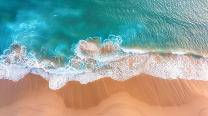 Natural beach scene from above, showcasing the interaction of soft sand with clear blue water waves, ideal for holiday wallpapers