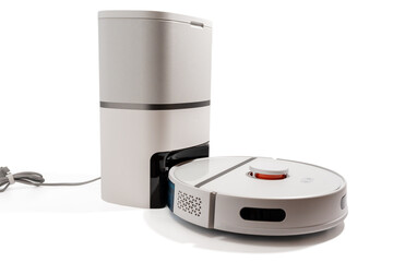 A white robot vacuum cleaner is on a white background. The robot is white and has a red button on...