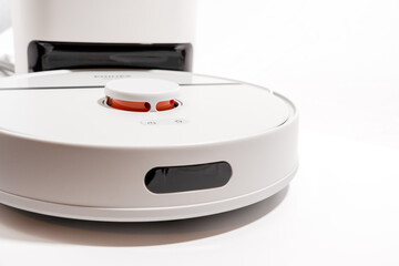 A white robot vacuum cleaner with a red button on the front.