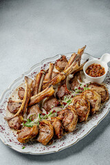 Lamb entrecote . Appetizingly cooked ribs served on a white platter with sauce. This image would be perfect for a restaurant menu or cooking blog. The ribs are perfectly grilled, garnished with herbs 