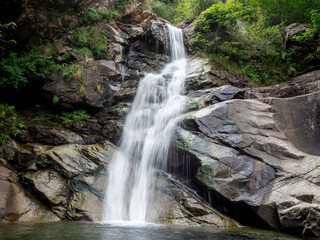 Long exposure shot of a beautiful waterfall formed by the Burdeiver creek. Surrounded by rocks and trees near Fondo in Valchiusella, Piemonte, Italy.