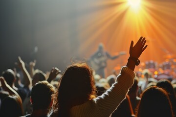 Back view of a person with raised hand at a concert with stage lights