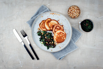 Traditional American pancakes with spinach, pine-nuts and raisins served as top view on a Nordic...