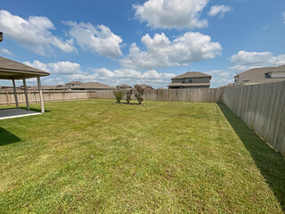 Suburban House Large Backyard with Wood Fence on a Cloudy Sky, Grass Maintained.