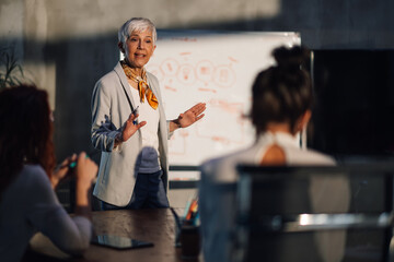 Senior female leader having presentation in front of her team at office