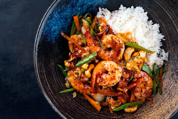 Traditional Thai fried king prawns with vegetable, cashew nuts and rice served as top view in a...