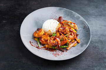 Traditional Thai fried king prawns with vegetable and rice served as close-up on a design plate with text space