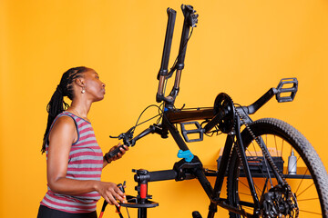 African american female meticulously examining bike components and fixing front fork with...