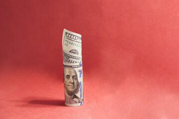 A one hundred dollar bill on a red background representing currency value fluctuations symbolically