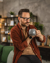 Adult caucasian man sit and hold coffee look out the window