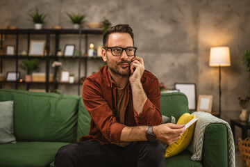 Portrait of adult man shop online and talk on mobile phone at home