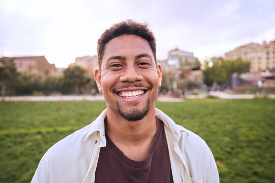 Handsome happy African American bearded man. Portrait of cheerful young man standing outdoors and smiling at camera. Positive emotion concept of male person. Generation z guy look carefree and natural