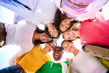 Low angle of a group of multiracial young only women looking at camera standing in a circle smiling...