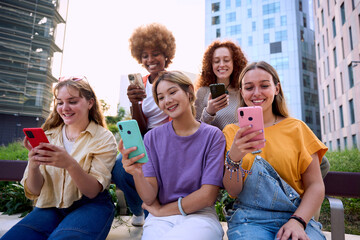 Multiracial happy smiling girl friends using phone and smiling together outdoor. Only women group...