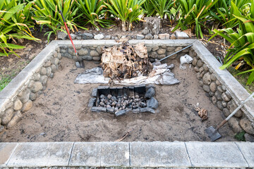 Hawaiian BBQ pit to cook a full pig for a luau, shovels and uses palm fronds remaining
