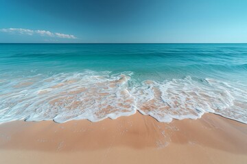 Bright sandy beach meets turquoise sea under a clear blue sky, with gentle waves lapping the shore - Powered by Adobe