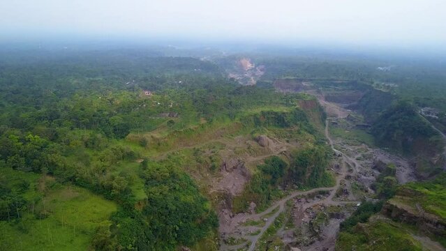 4k aerial footage of the area at the foot of Mount Merapi which consists of ravines that become lava flows, dense forests and hills that formed naturally when the mountain erupted some time ago