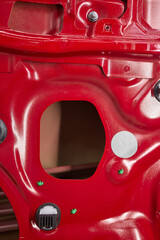 Closeup of red car door with perforated holes in automotive exterior