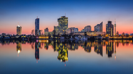 Fototapeta premium Vienna Cityscape at Dusk, Reflections on Danube with Illuminated Skyline