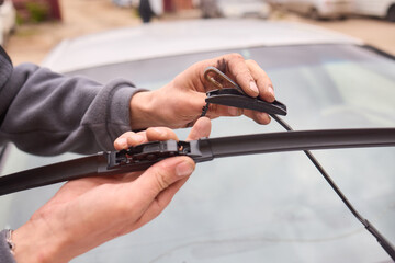 Hand changing car windshield wiper, using thumb and fingers