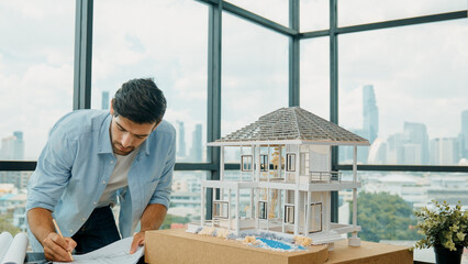 Professional architect engineer taking a note in blueprint house model. Businessman decide to...