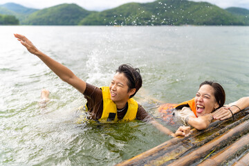 Young Asian woman friends with life vest and swim ring playing water together in the lake. Happy...