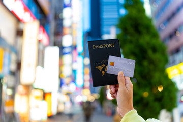 Asian woman hand holding passport and credit card with crowd of people shopping at Shibuya, Tokyo...