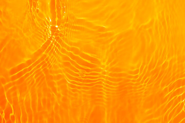 Orange water with ripples on the surface. Defocus blurred transparent gold colored clear calm water...