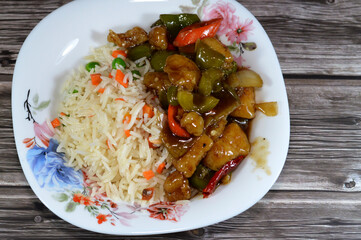 Traditional Chinese food cuisine of grilled chicken breast pieces with soy sauce, sweet and sour and chili chicken with vegetables, long grain white Basmati rice with vegetables carrots and peas