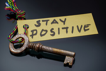 Key with STAY POSITIVE written on paper