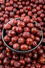 Fresh Jujube Fruits in a Metal Bowl on Pile Background, Close-up of fresh jujube fruits in a vintage metal bowl, surrounded by a pile of jujubes with a focused, glossy texture.