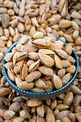 Fresh Almonds in a Bowl Over a Pile, Top View,Close-up view of fresh almonds in a decorative bowl, set against a background of loose almonds. Perfect for health and nutrition themes.