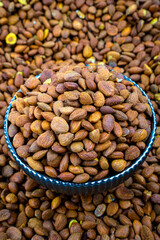 Bowl Of Salted Apricot Kernels Surrounded By Nuts