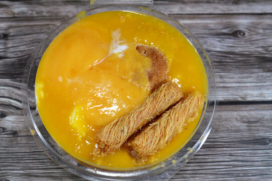A sweet mixture dessert of rice pudding, milk cream qishta, basbousa, konafa, ice cream, whipped cream, mango juice, pieces, milk and sugar, honey sugary syrup, sweet high calories bomb dessert mix