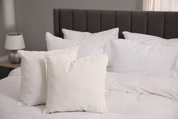 Many soft white pillows and duvet on bed indoors