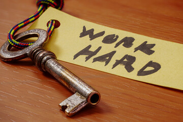 Key with WORK HARD written on paper
