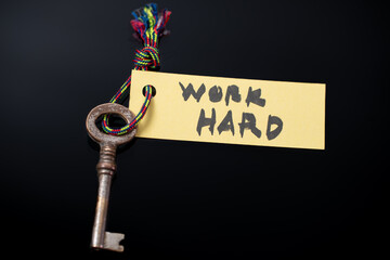 Key with WORK HARD written on paper