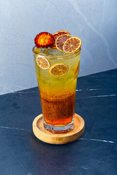 Refreshing Flixweed Saffron Drink with Citrus Garnish, A vibrant flixweed saffron drink served in a tall glass, garnished with dried citrus slices and a flower.