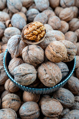 Fresh Walnuts in Shell in a Bowl Close-Up Shot, Close-up image capturing a bowl filled with fresh walnuts, some whole and one cracked open to show the edible part.