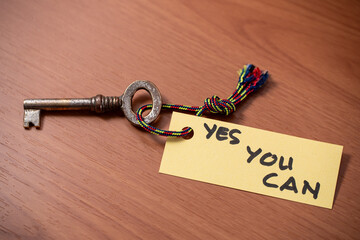 Key with YES YOU CAN written on paper