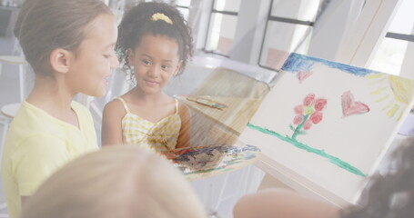 Image of paint brush over happy diverse schoolgirls talking and painting in art class