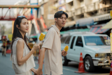 this adorable couple is eating and walking around at street food with happiness, they are dating on weekend at market, smiling because both of them are super satisfy being a couple