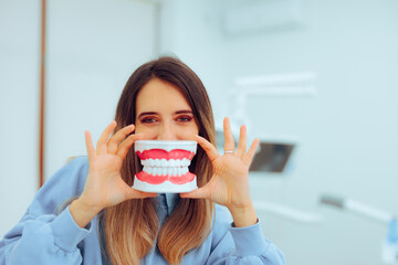 
Cheerful Patient Holding a Denture Model Smiling 
Funny woman with a big smile looking at the camera
